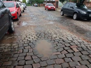 Rua pavimentada, mas cheia de buracos e com constantes alagamentos