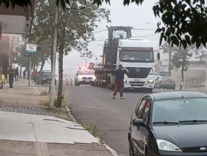 Caminhão carregado com trator causa estragos no centro