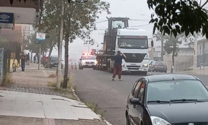 Caminhão carregado com trator causa estragos no centro