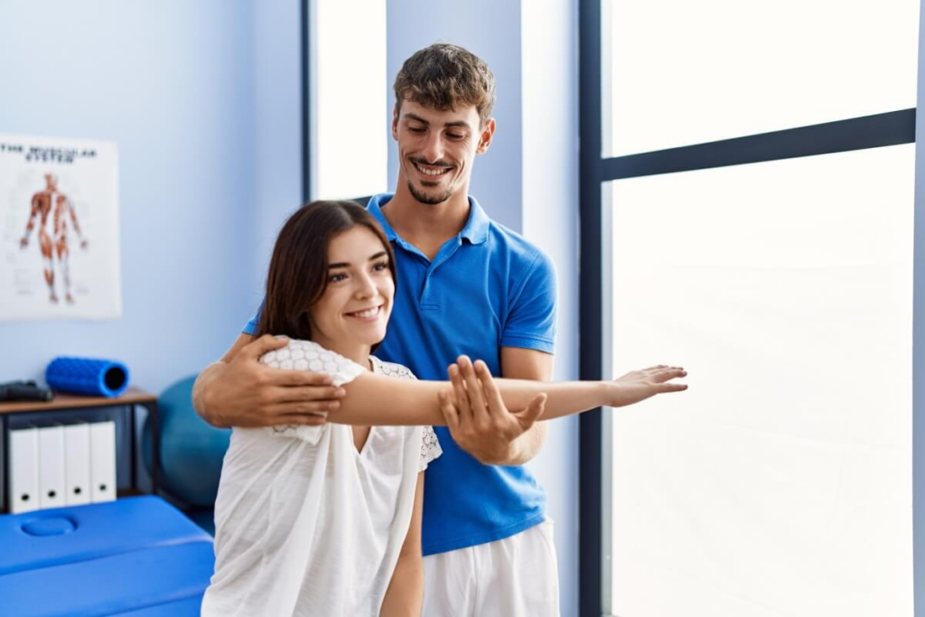 homem fisioterapeuta ajudando mulher jovem a fazer exercício na fisioterapia