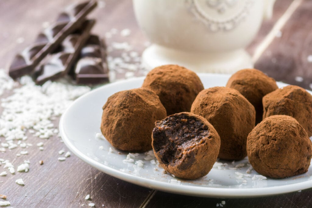 Brigadeiros em cima de um prato branco em uma mesa de madeira 