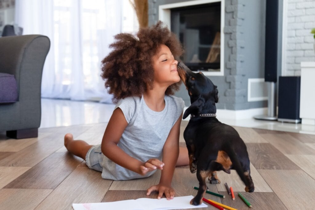 Criança brincando com cachorro na sala de casa