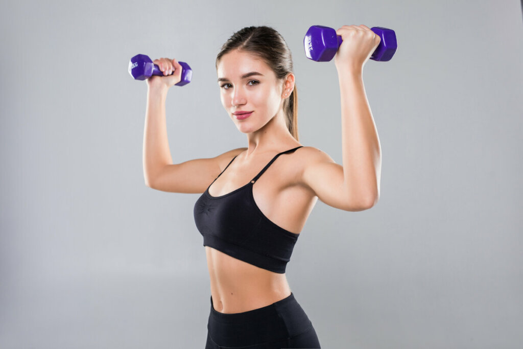 Mulher com roupa de academia preta levando peso