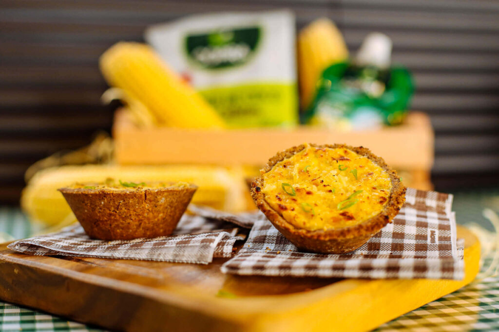 Quiche de milho-verde servido em guardanapos quadriculados em tábua de madeira