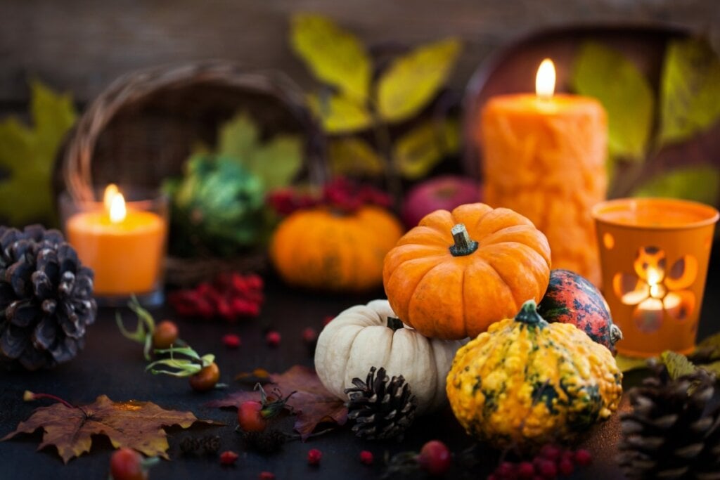 Velas laranja e mini abóboras em cima de uma mesa de madeira 