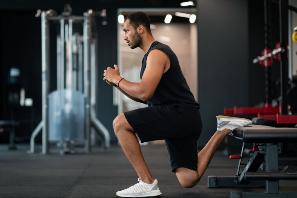 Homem fazendo agachamento unilateral em uma academia