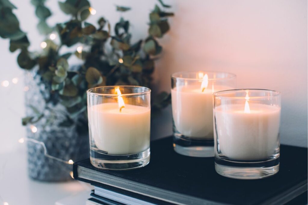 Três velas brancas ao lado de uma planta 