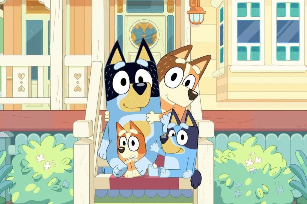 Imagem de desenho "Bluey" com Blue, Bingo, mãe e pai sentados na escada em frente à sua casa