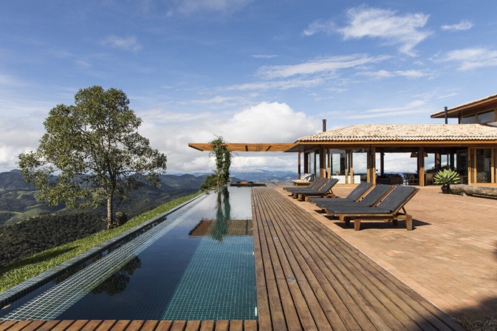 Piscina com borda infinita cercada por deck de madeira Cumaru, integrando arquitetura e paisagem natural