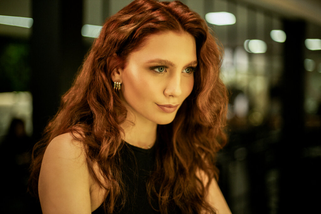 Mulher com o cabelo ruivo posando para foto em salão de beleza