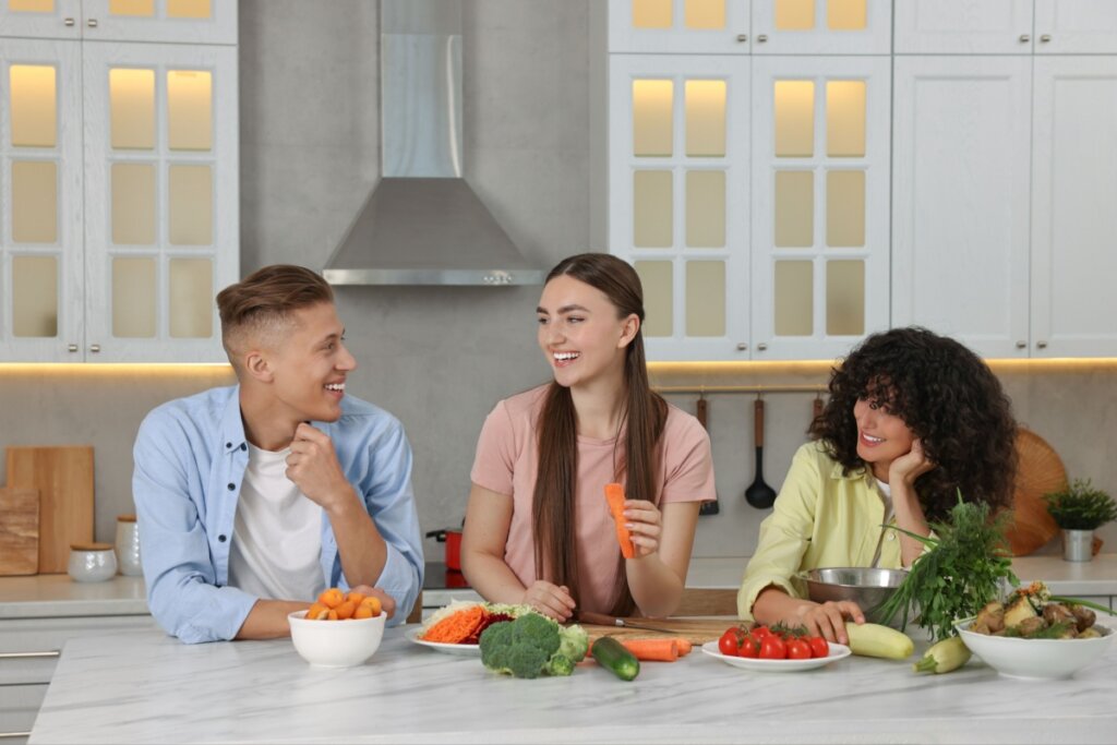 Três jovens na cozinha fazendo o almoço