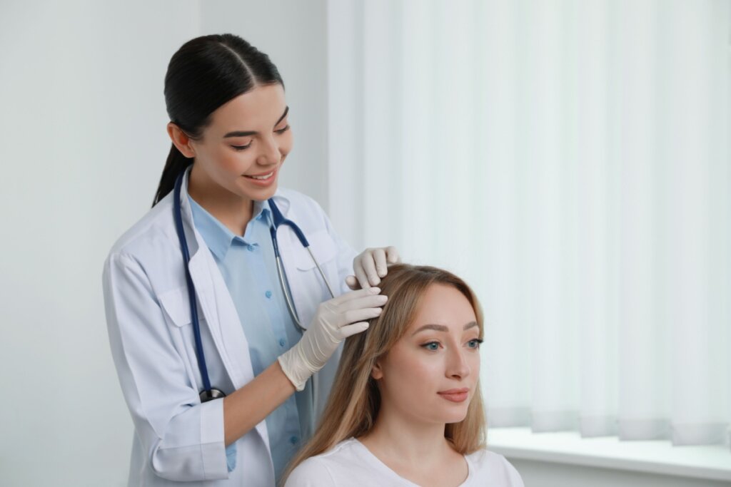 Mulher tendo o cabelo analisado por dermatologista em consultório