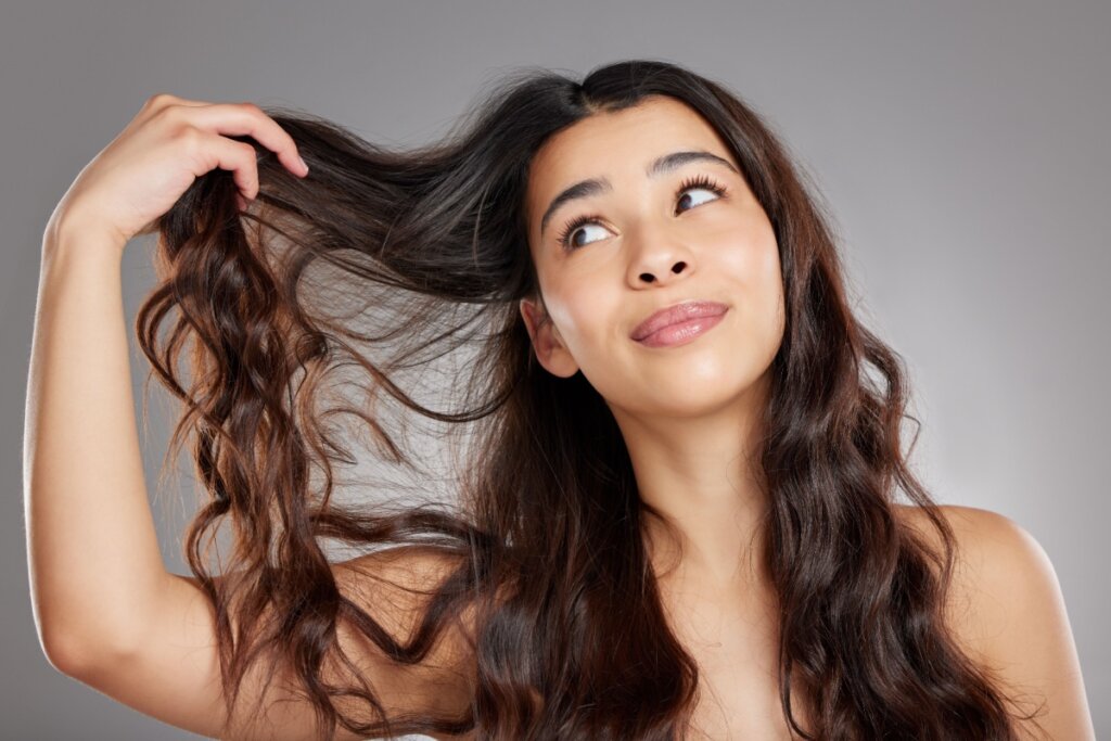 Mulher segurando uma mecha do próprio cabelo