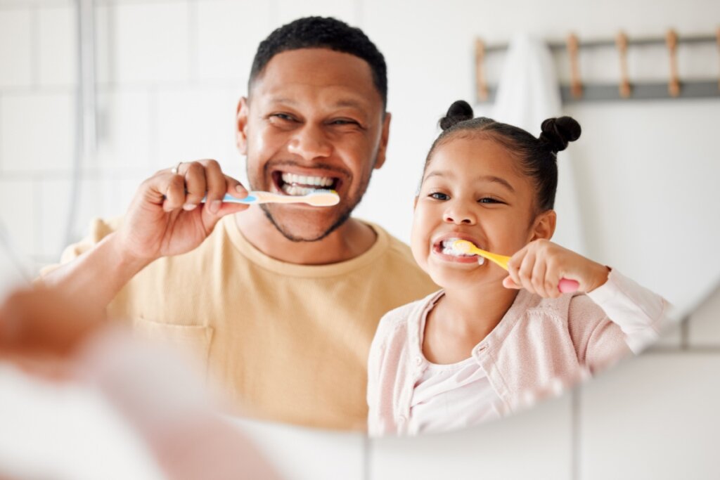 Pai e filha escovando o dente juntos