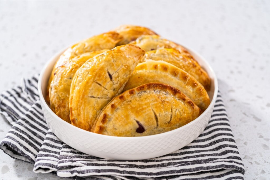 pote branco com pastéis assados em cima de pano listrado