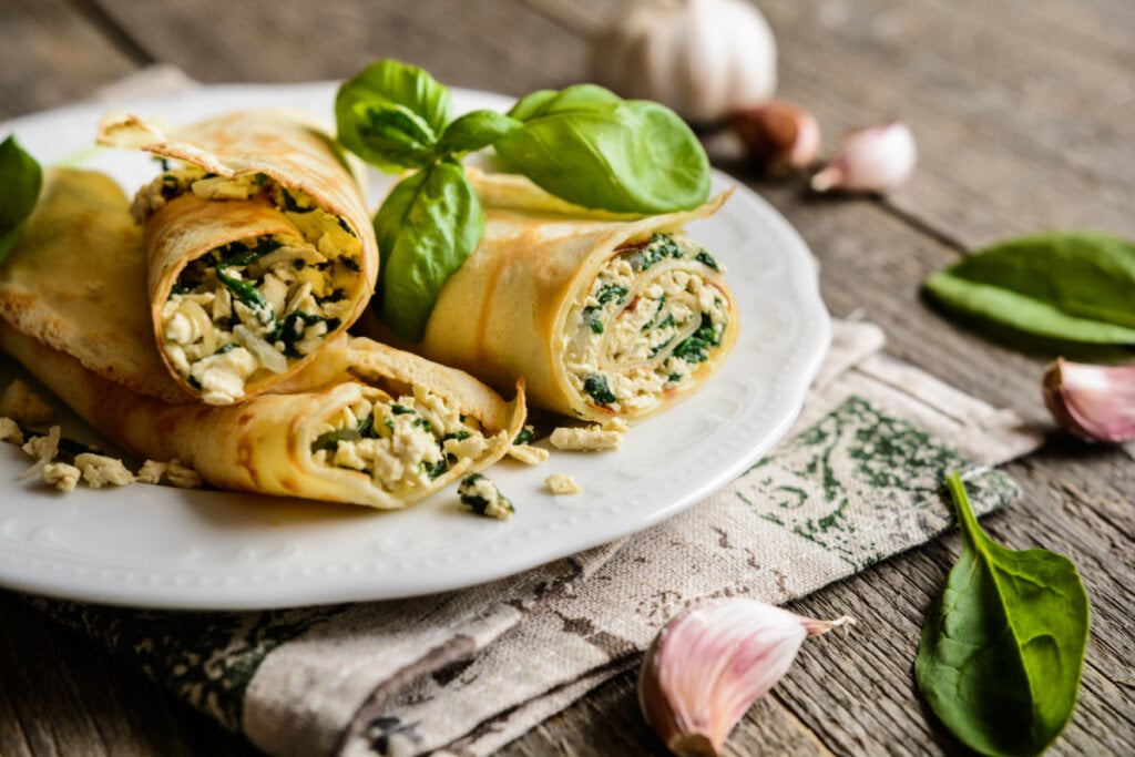 Três panquecas recheadas com tofu e espinafre em prato branco