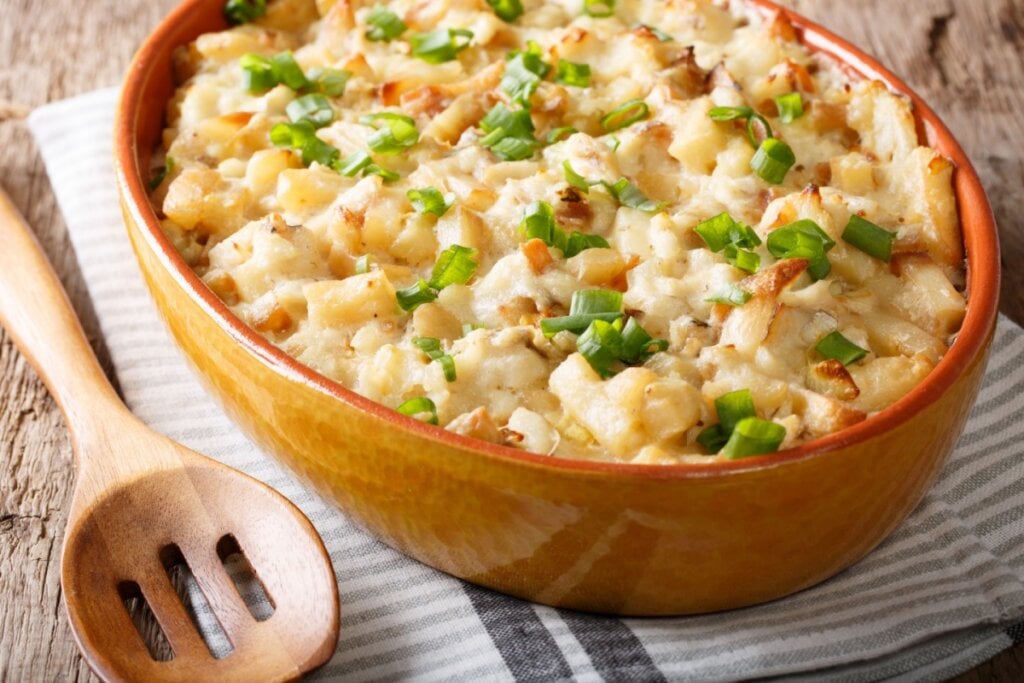 bacalhau com natas e cebolinha em recipiente marrom e colher de pau ao lado