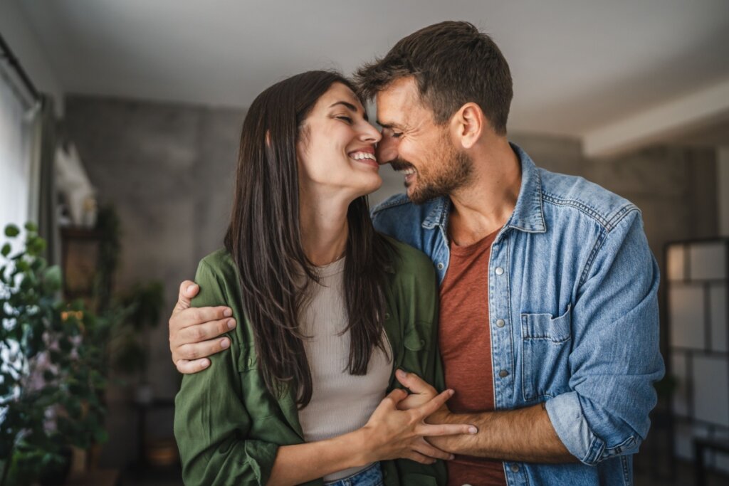 Casal feliz e abraçado com os rostos encostados um no outro