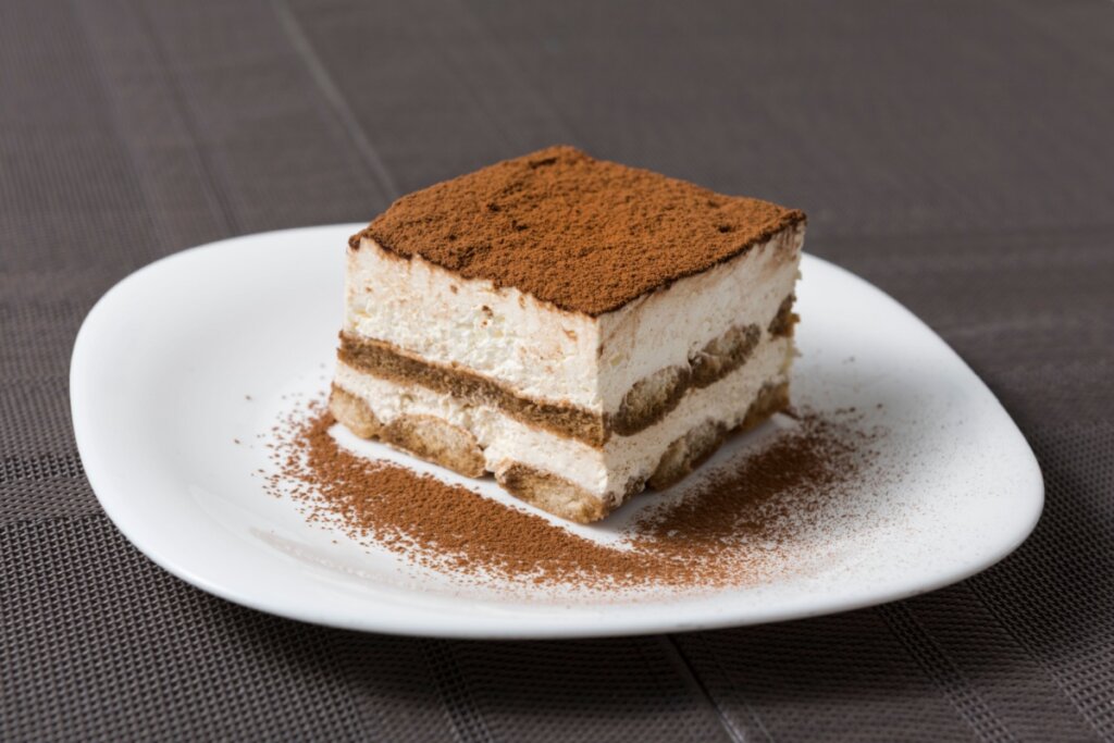 Pedaço de tiramisu servido em prato branco e porcelana 